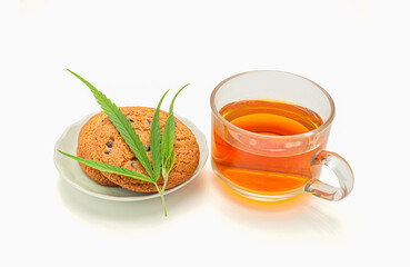 Cannabis chocolate chip cookies on a dish with a marijuana leaf and a glass of cannabis tea on a white background