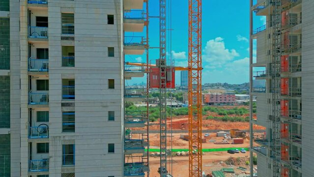 Freight elevator at the construction site of high rides up and down. A freight construction elevator rises to the top of a skyscraper. A temporary elevator is being built in the building. High-quality