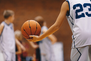 Junior level basketball player holding game ball at practice drill. Basketball training session for...