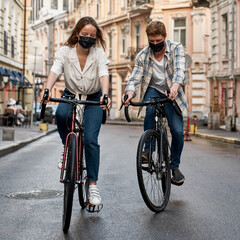 Couple wear masks ride bicycles in historical city