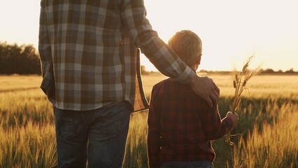 Farmer and his son in front of a sunset agricultural landscape. Man and a boy in a countryside...