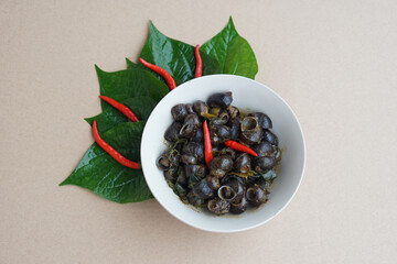 Bowl of Thai traditional food, curry freshwater snails with green leaves and red chilies. Concept :  Thai local food in northern of Thailand. Cooking and eating cuisine.          © Sanhanat