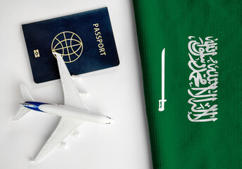 Flag of Saudi Arabia with passport and toy airplane. Flight travel concept
