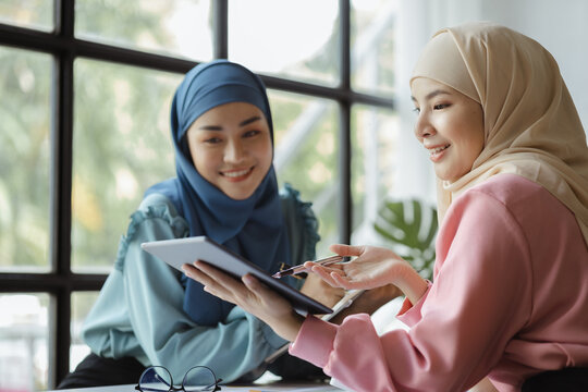 Two Hijab-clad Asian Women Are Brainstorming Together In A Conference Room For A Startup, Run By A Young, Talented Woman. The Management Concept Runs The Company Of Female Leaders To Grow The Company.