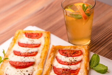mini pizzas with tomatoes and mozzarella. and homemade lemonade on a wooden table. Side, close-up.