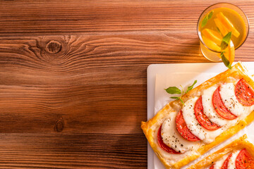 mini pizza with tomatoes and mozzarella. homemade lemonade on a wooden table. From above
