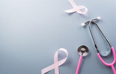 Pink ribbon and stethoscope on pastel paper background for supporting breast cancer awareness month campaign.