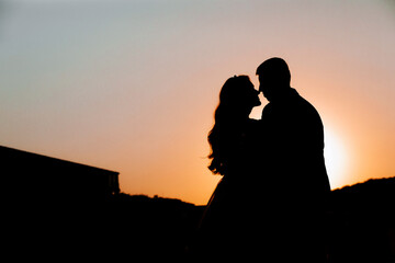 Silhouette of a young bride and groom on the background of the sunset