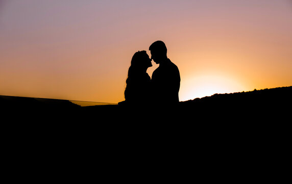 Wedding silhouette couple of lovers kissing on sunset with evening sky background