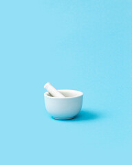 White pharmacy mortar and pestle on the blue background. Visual concept.