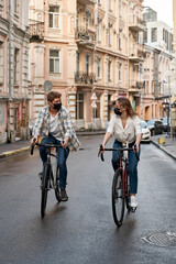 Young caucasian couple wear masks ride bicycles