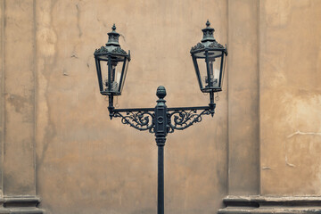 Fototapeta na wymiar Vintage street lanterns on metal pole against concrete old wall at urban street outdoor toned in sepia