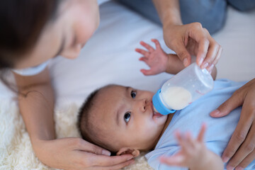 Young Mom and father laughing joyful proud teasing playing kiss cheek and feet arm hold asian...