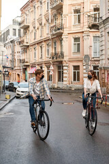 Obraz na płótnie Canvas Couple wear medical masks ride bicycles in city