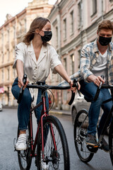 Fototapeta na wymiar Man and girl wearing medical masks riding bicycles