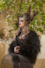 Girl in the mystical image of the queen of birds with a cage in her hands