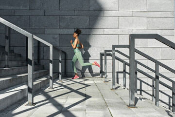 Black sportswoman running or jogging on staircase