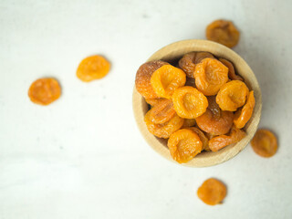 dried apricots in a wooden bowl on a gray concrete table, dried fruits