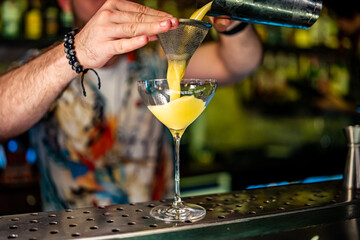 man hand bartender pouring cocktail in glass on the bar counter