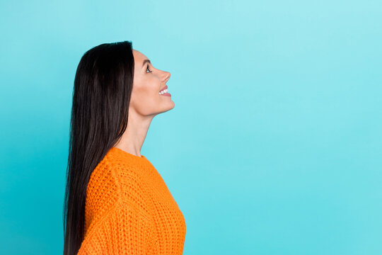 Profile portrait of adorable cheerful person beaming smile look interested up empty space isolated on cyan color background