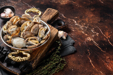 Garlic white wine shells Clams, vongole in a skillet with herbs. Dark background. Top view. Copy...