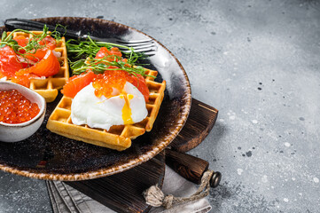 Belgian waffle with cream cheese, salmon slices, egg and red caviar. Gray background. Top view....