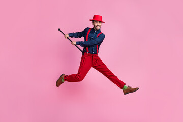 Full size photo of excited carefree man hold stick cane jumping isolated on pink color background