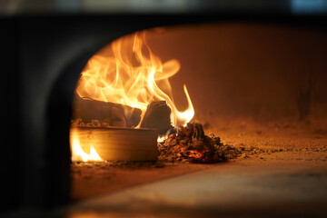 Chef puts Italian pizza in a wood-fired oven