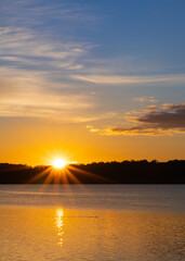 sunrise starburst over lake with otter
