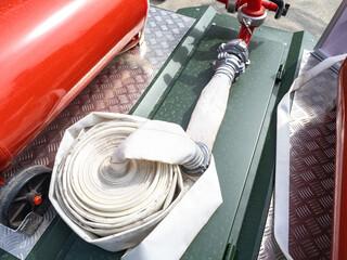 Firehose on metal surface. Fire fighting equipment. Firehose near red cylinder. Fire fighting...