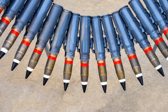 Large caliber warheads. Supplies for machine gun above ground. Blue high-caliber cartridges. Military ammunition belt. Military-industrial complex. Air Force ammunition. Ribbon warheads close-up