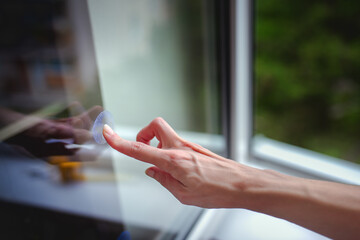 A woman's hand sticks decals on windows for birds. These decals has a special coating that reflects...
