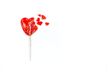 Broken heart shaped lollipop on white background