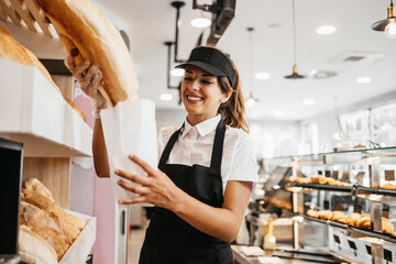 Beautiful young and happy female worker working in a modern bakery or fast food restaurant.
