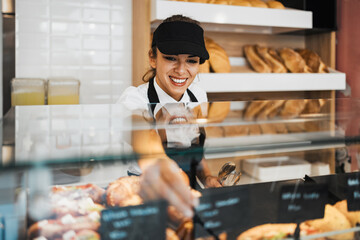Beautiful young and happy female worker working in a modern bakery or fast food restaurant.