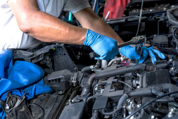 Close up car mechanic hands with working gloves fixing car problems in vehicle repair service, Car maintenance concept
