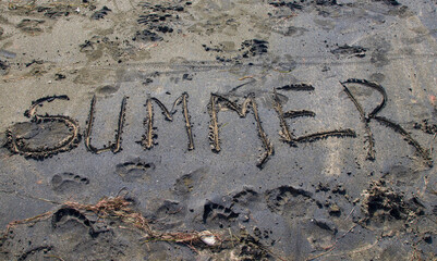 inscription on the sand, word summer written on black sand at sea beach, summer time