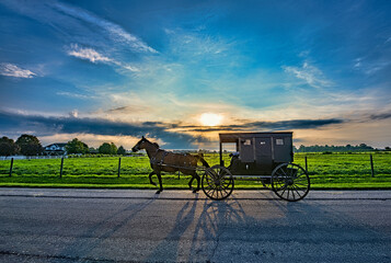 Fototapeta na wymiar Amish Buggy with shadows on the road at sunrise in rural Indiana.