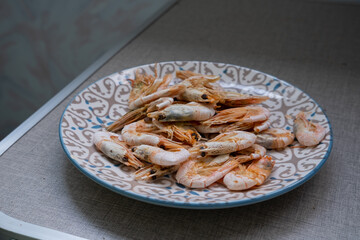 Shrimps, in a plate on the table, prepared at home on an electric grill