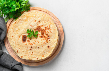 Chapati, traditional Indian flatbreads with fresh herbs on a gray background. Top view, copy space