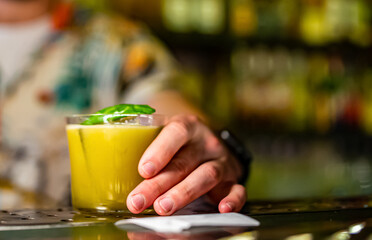 man hand bartender holding cocktail in glass on the bar counter