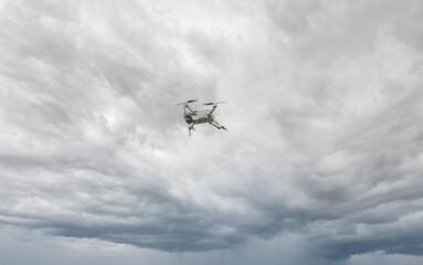 A high-tech drone in the sky Professional filming drone flies in the air at a low altitude against a blue sky and sea sandy beach. The drone makes photos. Modern new technology.