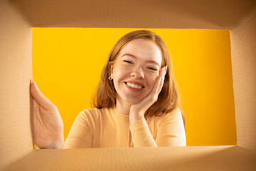 Happy smiling young girl looking inside box during opening, unpacking it. Emotions, black friday,...