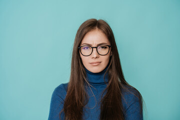 Upset caucasian young woman in glasses over turquoise studio background looking at camera with offended face expression. People emotions, bad news. Mockup, failure, mistake, dissapointment.