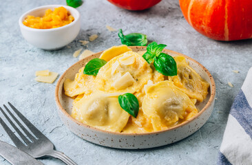 Homemade Pumpkin Ravioli with sauce and bsil on concrete background. Autumn food concept. Selective focus