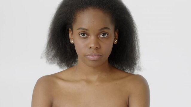 Beauty Woman face Portrait. Attractive Spa model Girl with Perfect Fresh Clean Skin. African American Female with Black Curly Hair with naked shoulders opening her Beautiful Eyes and looking at camera