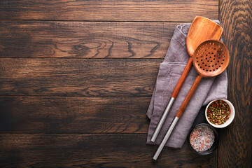 Fototapeta na wymiar Cooking wooden utensils, basil leaves and spices on old wooden background. Abstract food background. Top view of dark rustic kitchen table with wooden cooking spoon, frame. Banner for your design.