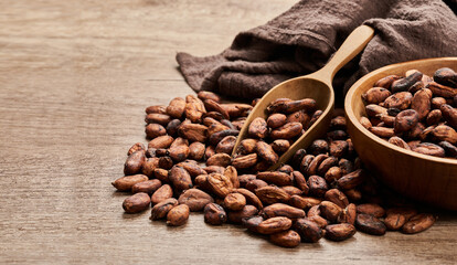 cocoa seed or cacao beans with wood scoop and bowl in wooden table background              