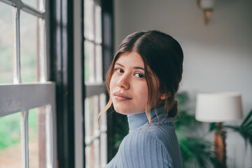 Portrait of one young beautiful and attractive woman smiling and enjoying having fun looking at the camera alone at home. Close up of female person relaxing indoor..