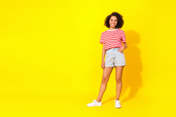 Fototapeta na wymiar Full length photo of young girl buy cool outfit red stripped t-shirt shorts white sneakers isolated on yellow color background